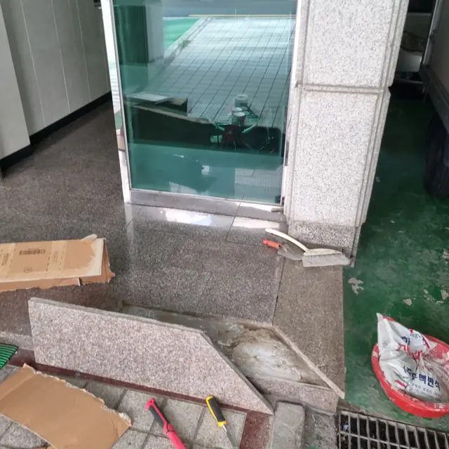 출입구 계단 모서리 대리석이 삼각형으로 크게 깨져 나간 노후 손상 모습